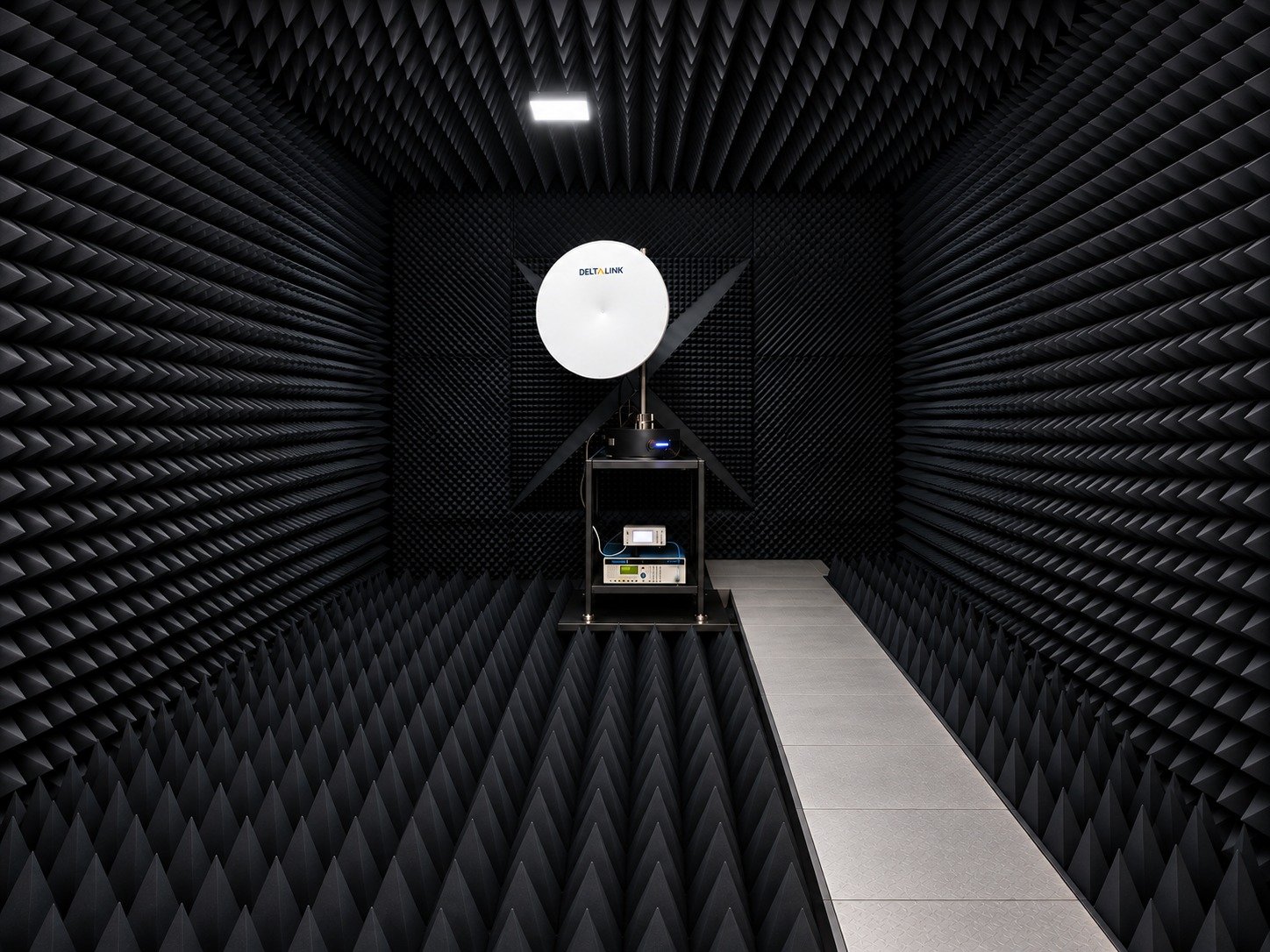 Deltalink dish antenna inside an RF absorber-lined measurement chamber.